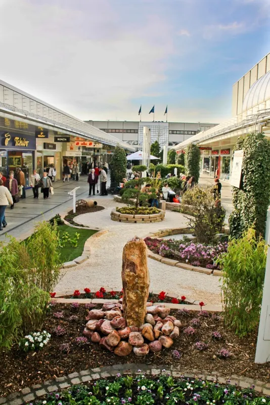 Ausstellungsgarten mit runder Pflanzfläche und Blumenbeeten in der Ladenstraße des Ruhrparks Bochum